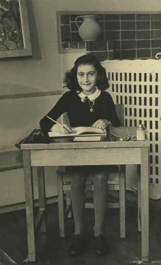 Anne Frank sitting behind a desk