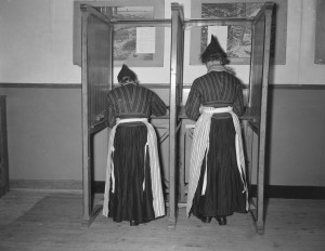 Women in traditional costume in a voting booth.