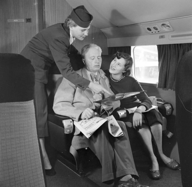 flight attendent helping passengers on a plane