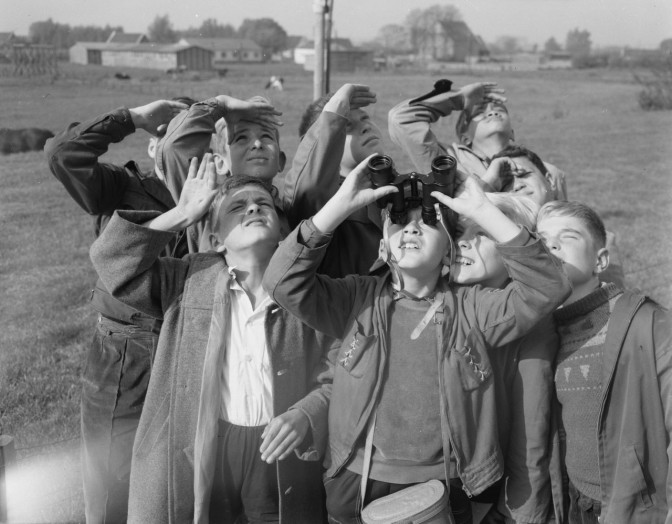 Boys looking up with binoculars