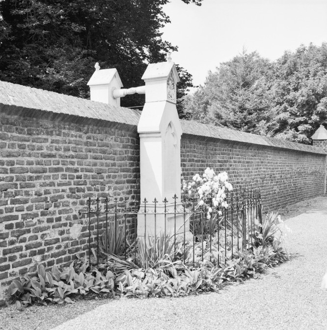 Two grave markers on opposite sides of a wall, holding hands above the wall