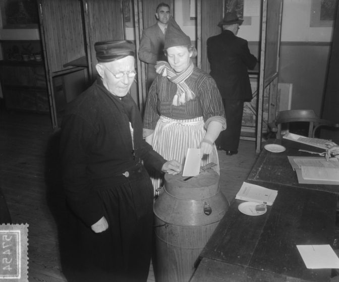 man and women in Volendam costume casting a ballot 