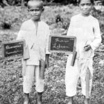 two boys showing blackboards with their names